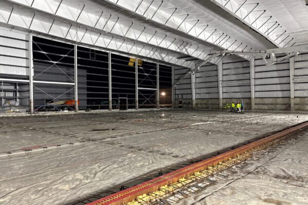 Interior view of a large steel building under construction at night