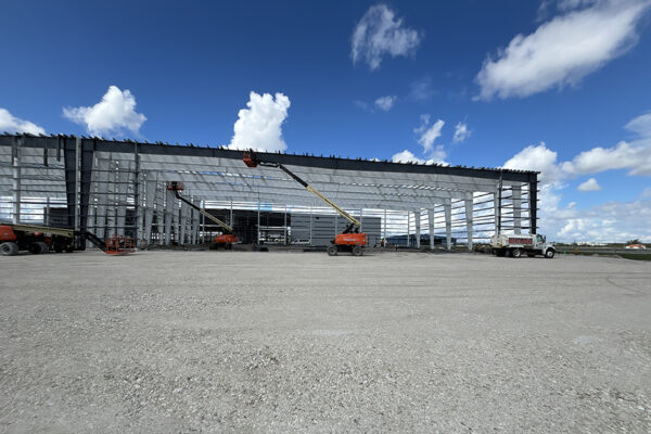 Steel aircraft hangar under construction with lifts and trucks