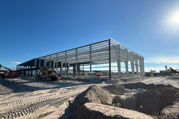 Steel aircraft hangar under construction with excavator and site equipment