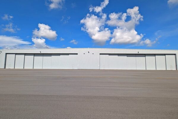 Pre-engineered steel airplane hangar at Skybridge Miami Opa-Locka Airport with two sets of closed stacking hangar doors facing the apron