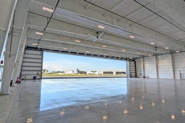 Empty pre-engineered steel airplane hangar at Skybridge Miami Opa-Locka Airport with the full-width hangar door open to the flight line