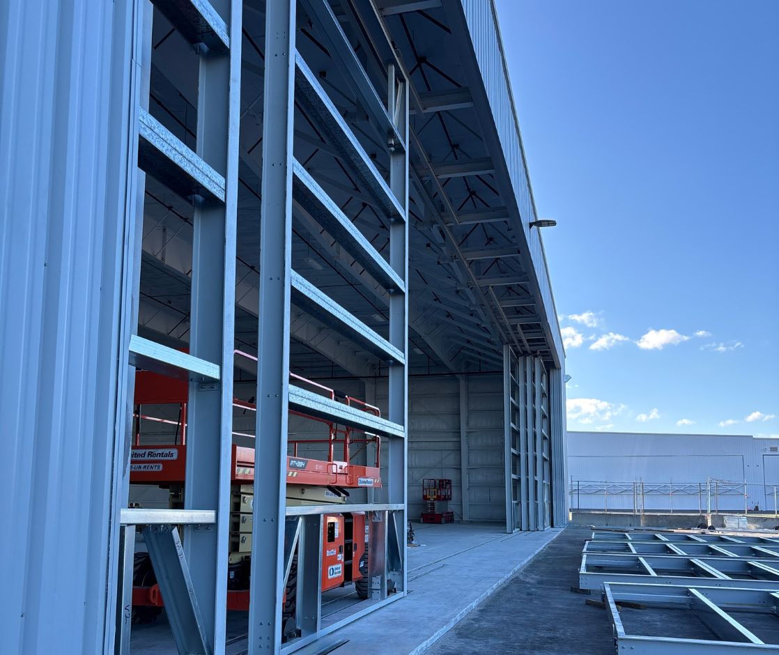 Industrial warehouse under construction with steel framing and lift equipment