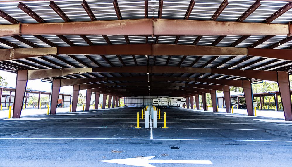 Covered vehicle storage with parked camper and metal canopy