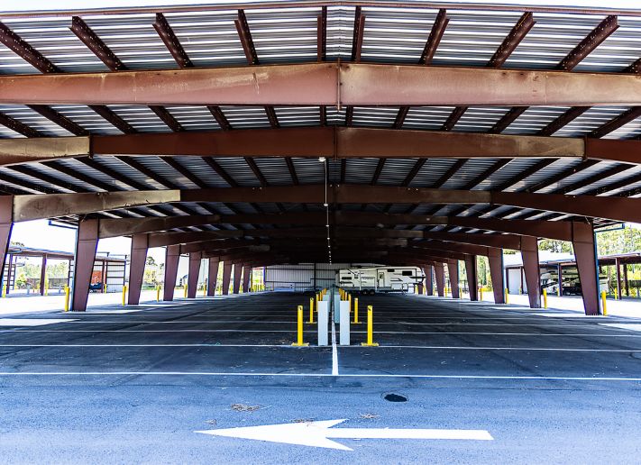 Covered vehicle storage with parked camper and metal canopy