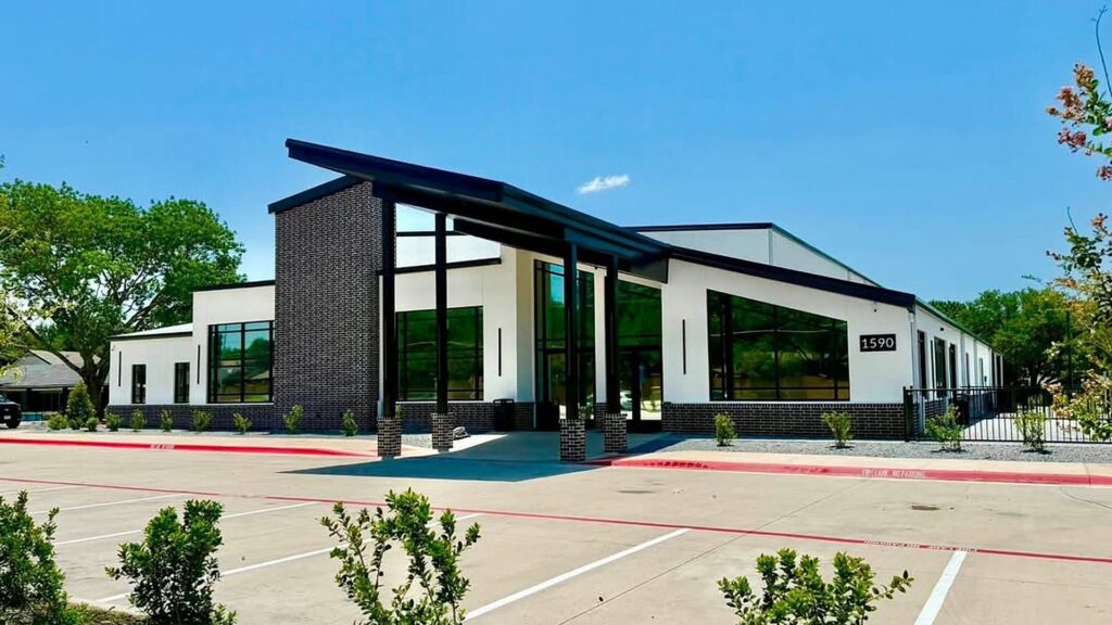 Front elevation of Zion Church, a metal church campus in Richardson, TX, with a brick tower and covered drop-off canopy
