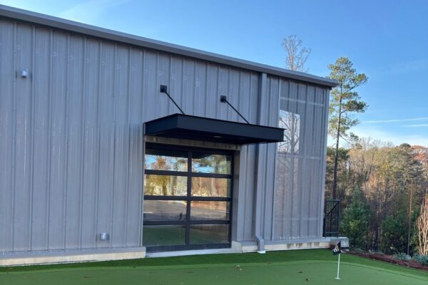 Glazed garage door opening onto an indoor putting green inside the Ruby-Collins metal office building in Smyrna, GA