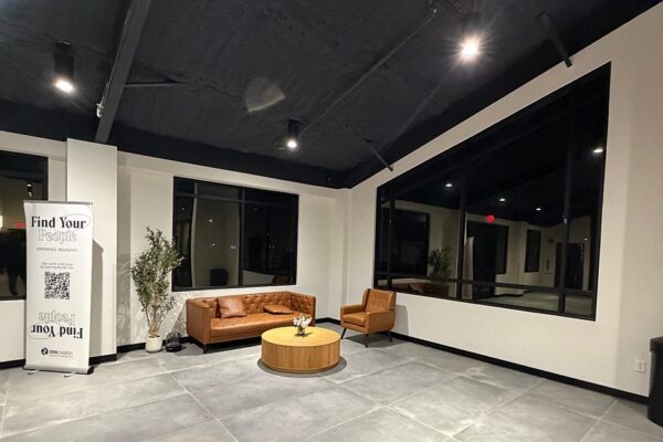 Lounge seating area in the Zion Church lobby with interior windows and an exposed black ceiling