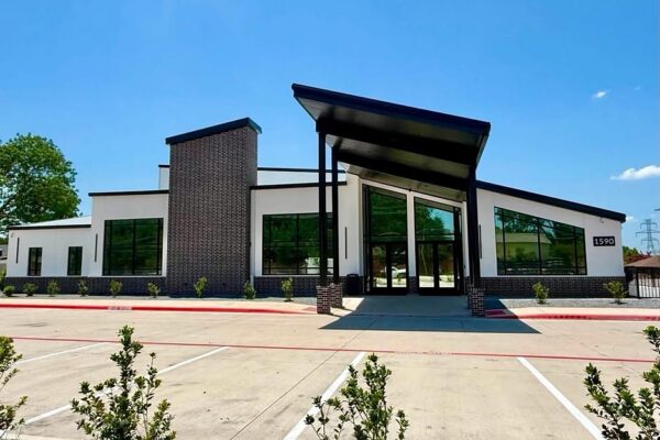 Main entrance facade of Zion Church in Richardson, TX, with a sloped canopy over glass entry doors
