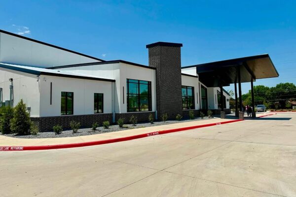 Side elevation of a metal church building in Richardson, TX, with white wall panels, brick wainscot, and a brick chimney feature